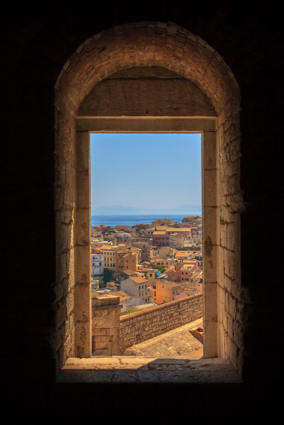 Free Image of Ancient window framing a cityscape view 
