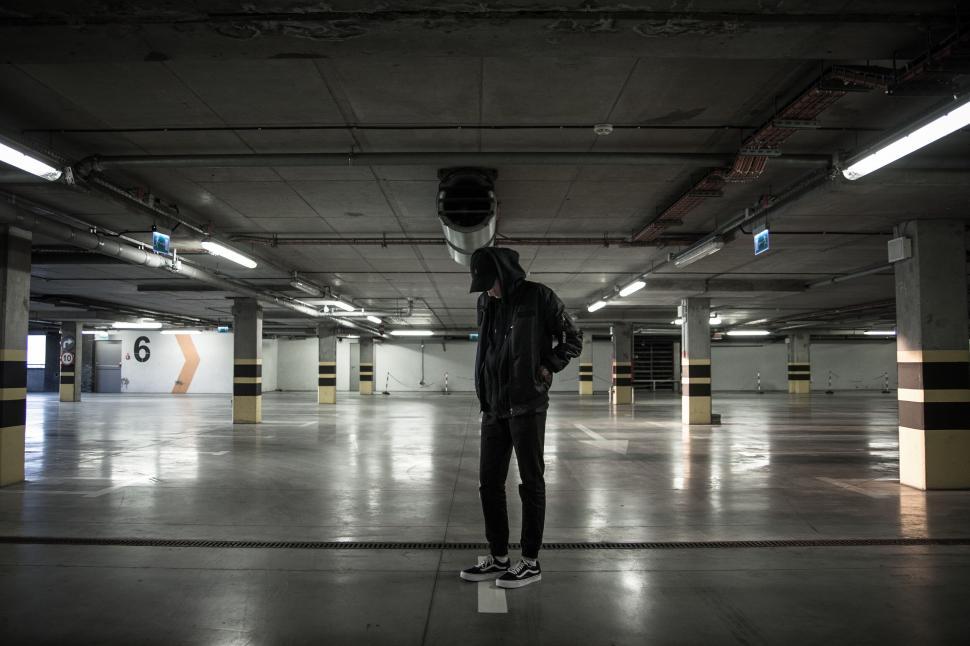 Free Image of Lone figure in a dimly lit parking garage 