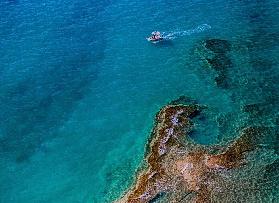 Free Image of Aerial view of a boat on crystal-clear waters 