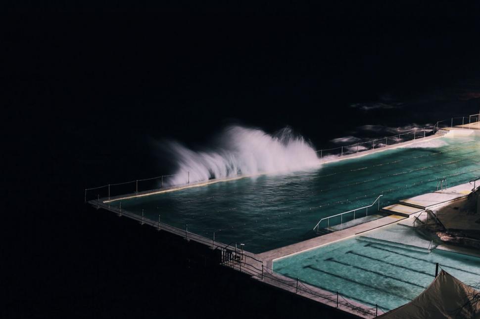 Free Image of Night view of ocean waves crashing into pool 