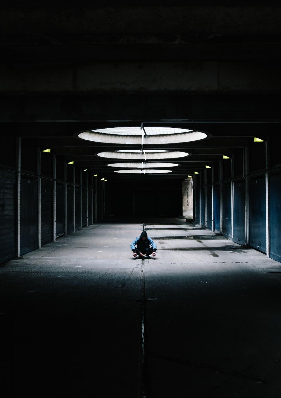 Free Image of Person sitting alone under circular light 