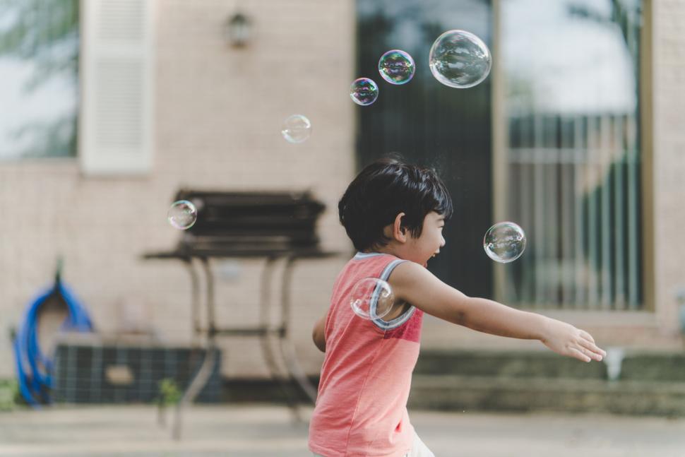 Free Image of Child chasing bubbles in front of house 