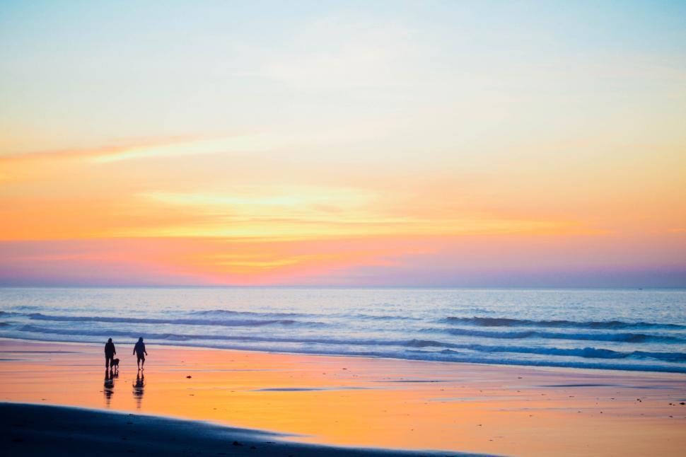 Free Image of Couple walking on beach at sunset 