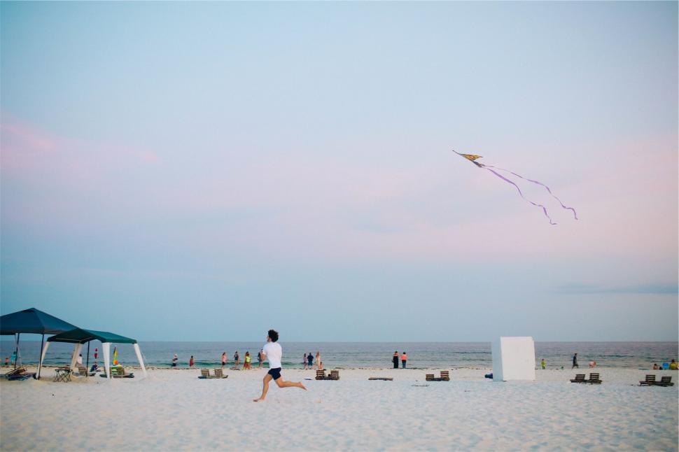 Free Image of Man with a kite on a beach at dusk 