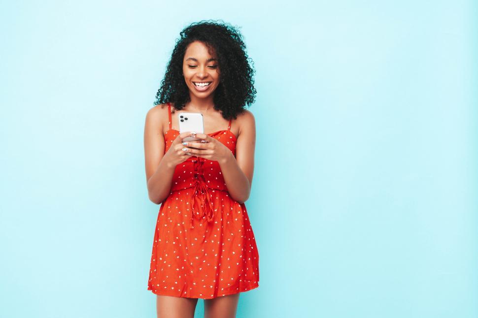 Free Image of A woman in a red dress holding a phone 