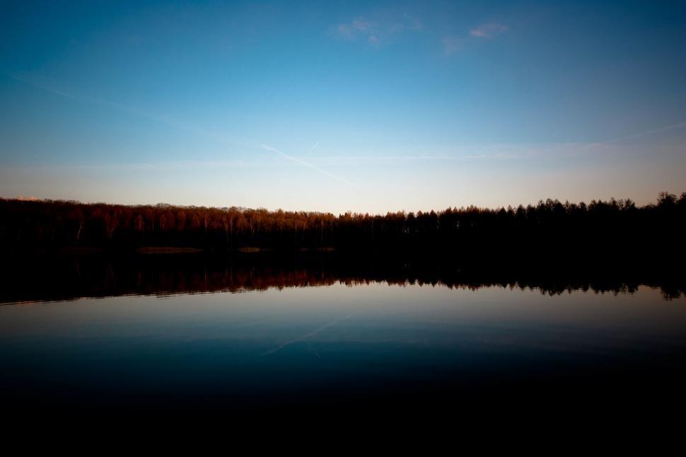Free Image of Tranquil lake at sunset with forest silhouette 