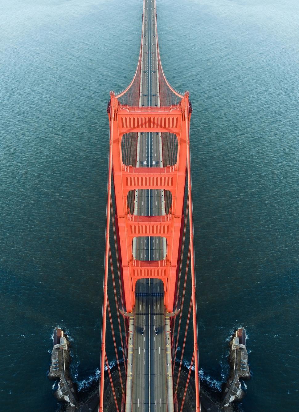 Free Image of Close-up of orange suspension bridge tower against blue water 