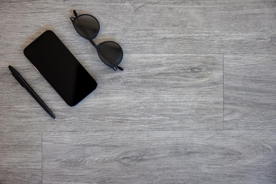Free Image of Smartphone sunglasses and pen on wood 