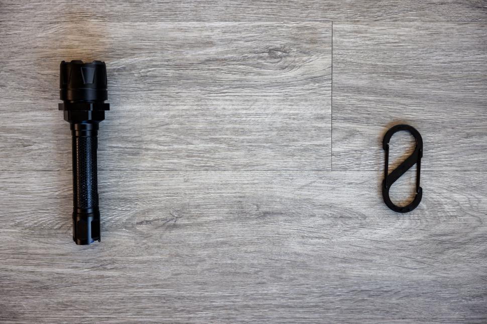 Free Image of Black flashlight and carabiner on wooden floor 