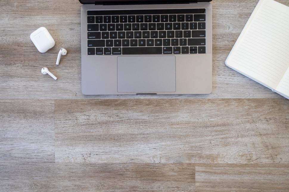 Free Image of Laptop on a wooden floor with an open notebook 