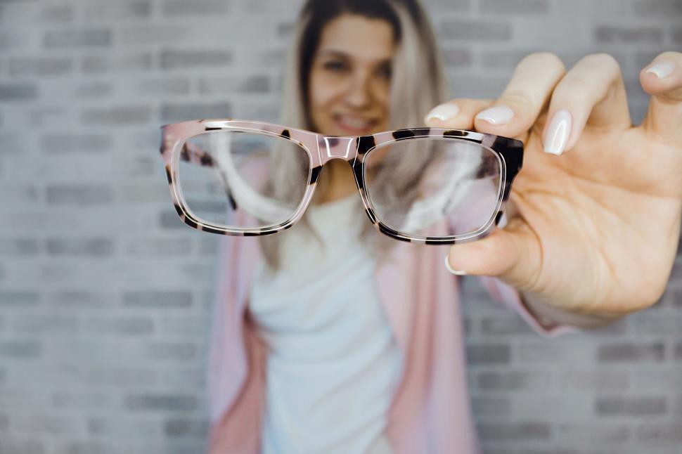 Free Image of Woman holding glasses in focus with smile 