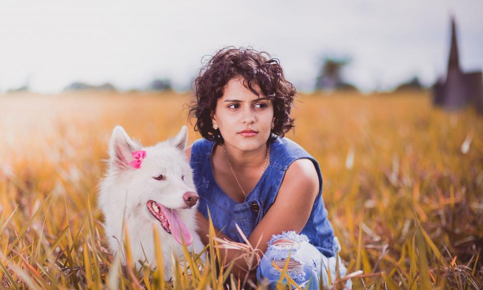 Free Image of Woman and white dog sitting in field 