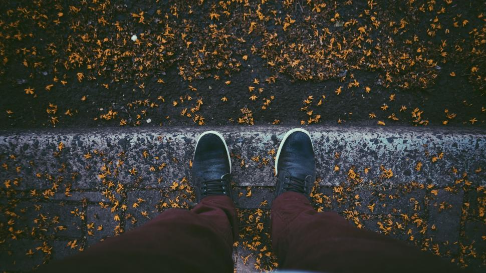 Free Image of Looking down on feet with fallen leaves around 