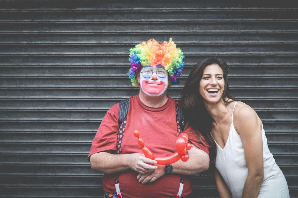 Free Image of Woman laughing with clown holding balloon animals 