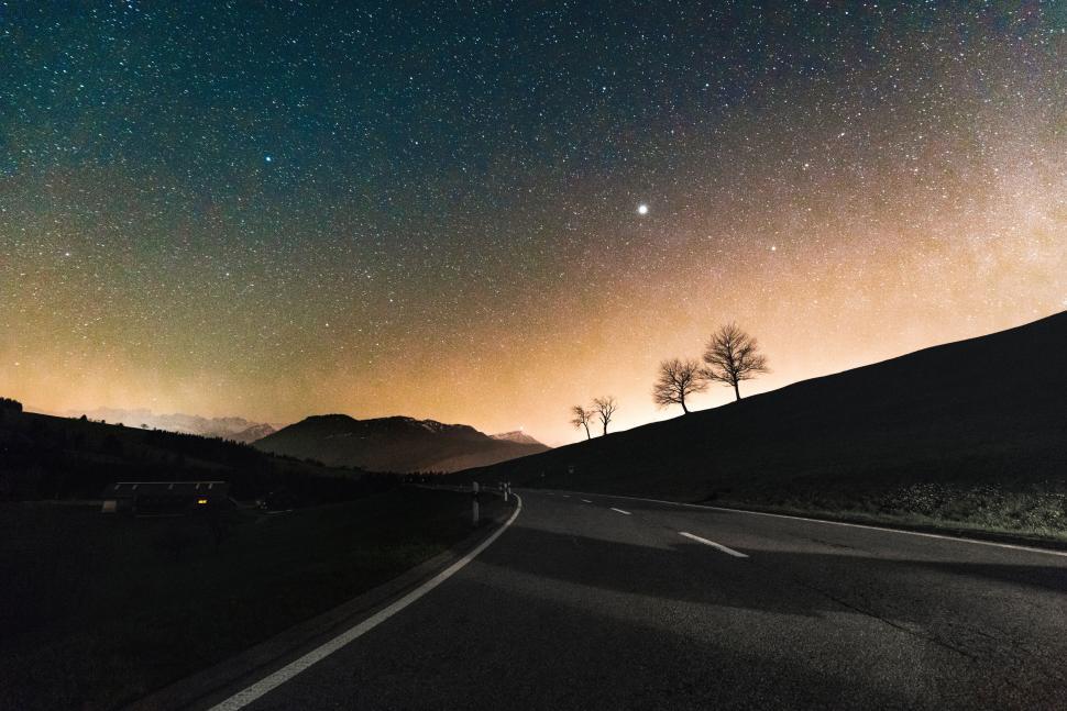 Free Image of Starry night sky above a mountain road 