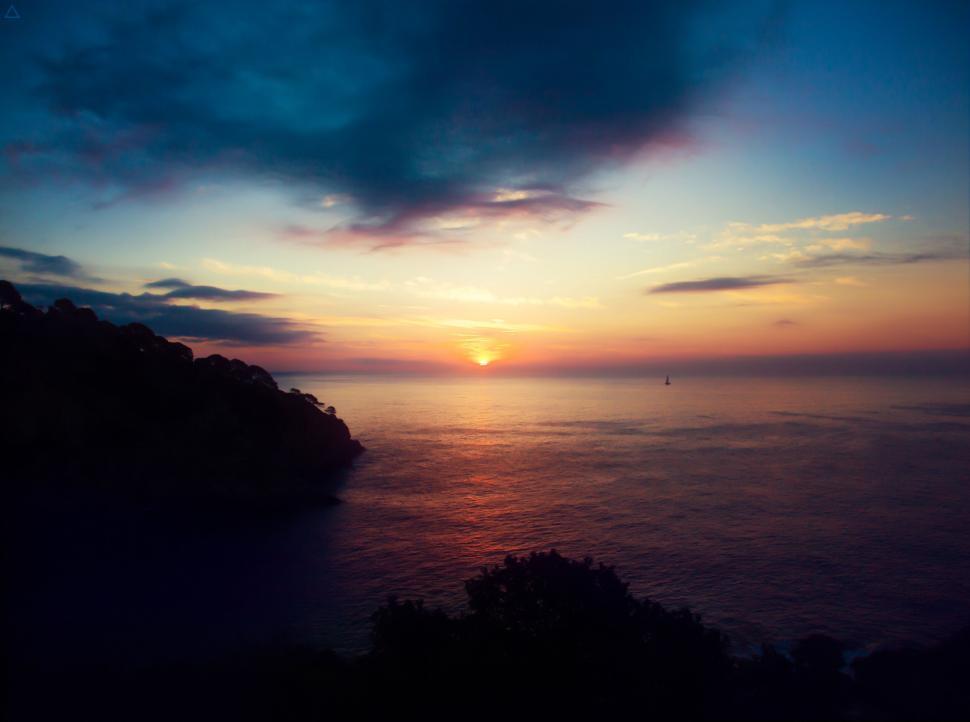 Free Image of Sunrise over ocean with silhouetted coast 
