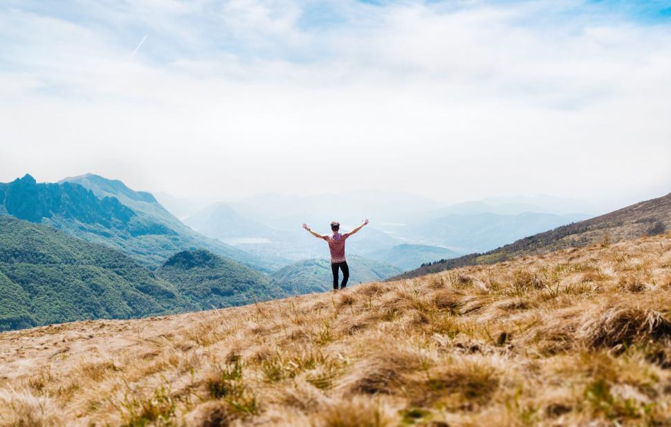 Free Image of Man with arms raised on mountain slope 