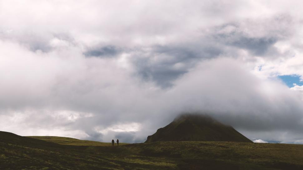 Free Image of Silhouettes walking in cloudy mountain scene 