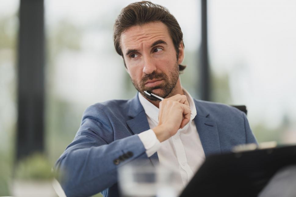 Free Image of Thoughtful businessman with pen at modern office 