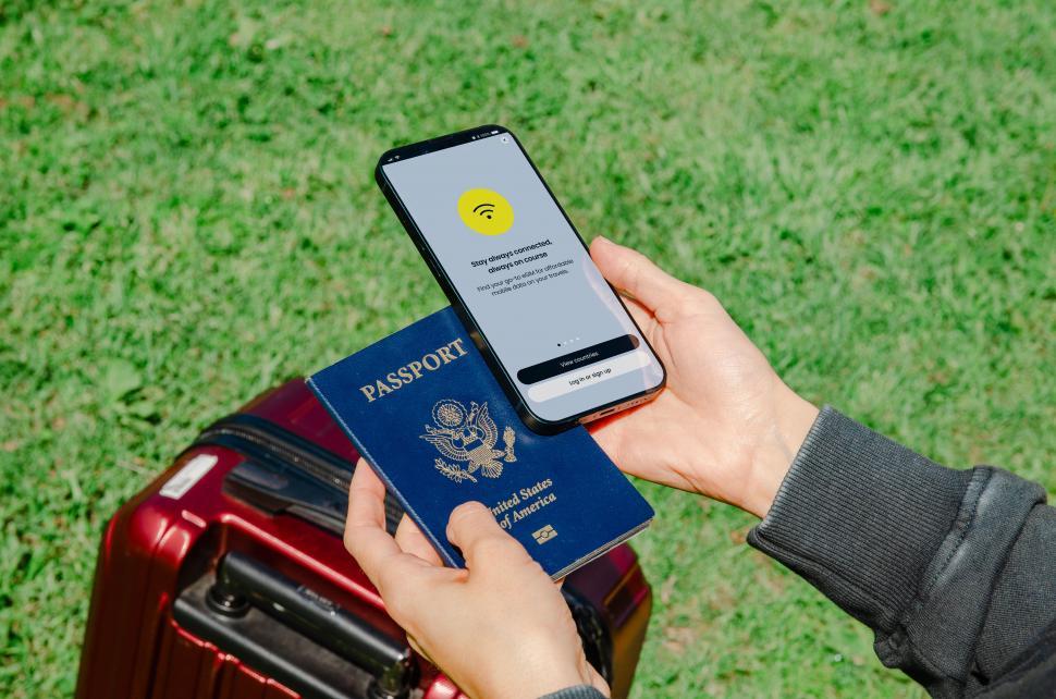 Free Image of A hand holding both a passport and a phone with an eSIM, indicating the modern necessities for international travel  