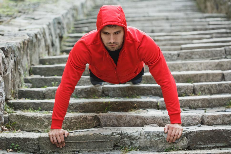 Free Image of Man doing a push-up on stone stairs 