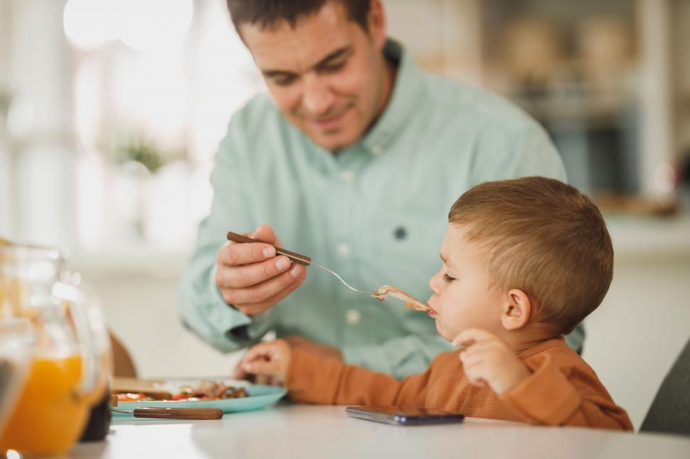Free Image of Father feeding young son at breakfast table 