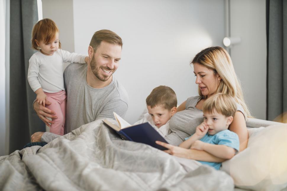 Free Image of Family reading a book together in bed 