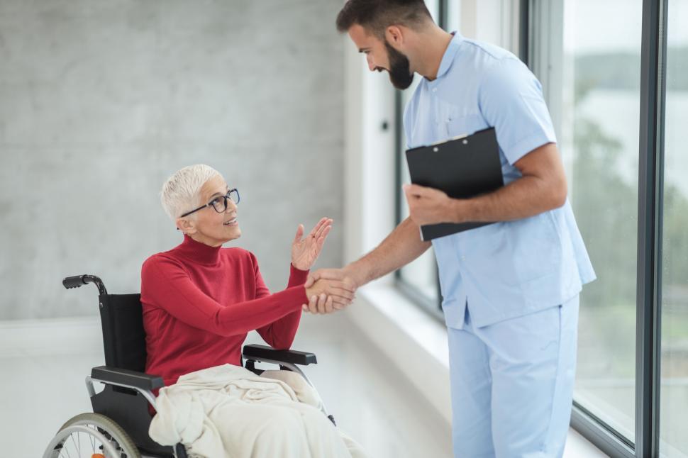 Free Image of Nurse greeting elderly patient in wheelchair 