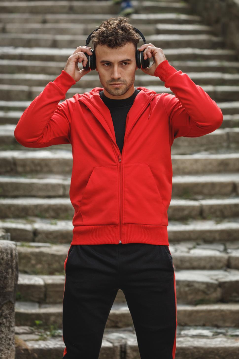 Free Image of Man in red jacket with headphones outdoors 