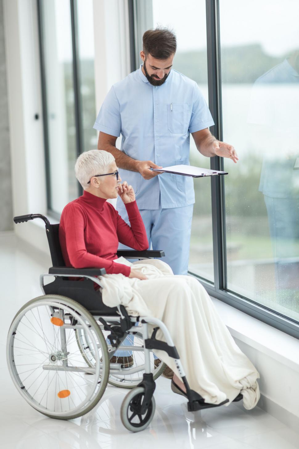 Free Image of Nurse with patient in wheelchair by the window 