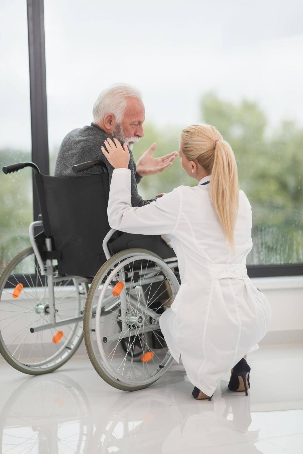 Free Image of Nurse comforting elderly man in wheelchair 