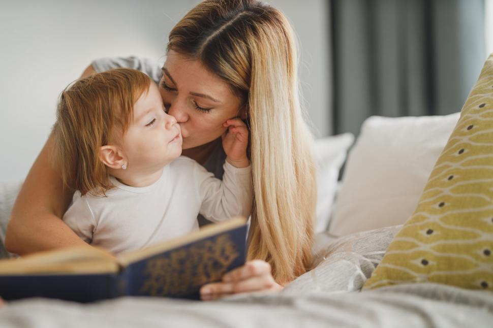 Free Image of Mother reading to child on bed with affection 
