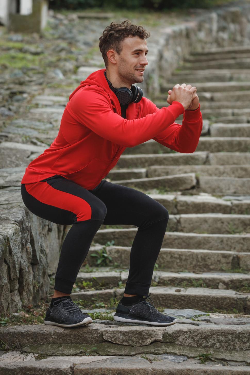 Free Image of Man doing squats outdoors on stone steps 
