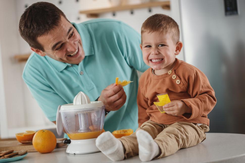 Free Image of Father and toddler son having fun with juicer 