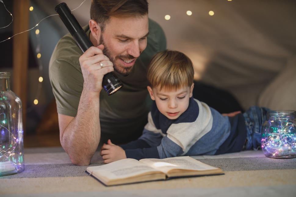 Free Image of Father and son reading under fairy lights 