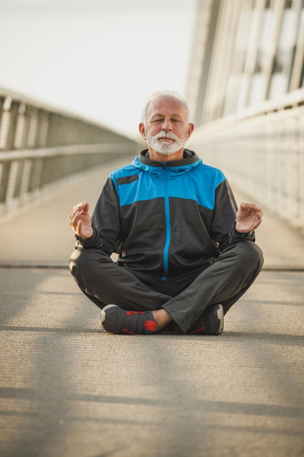 Free Image of Senior man practicing yoga on a bridge 