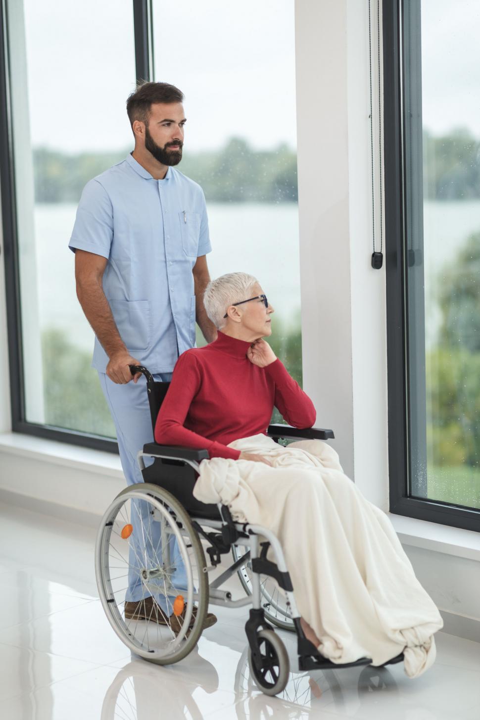 Free Image of Male nurse pushing a woman in a wheelchair 