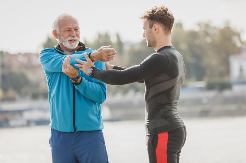 Free Image of Senior man stretching with trainer outdoors 