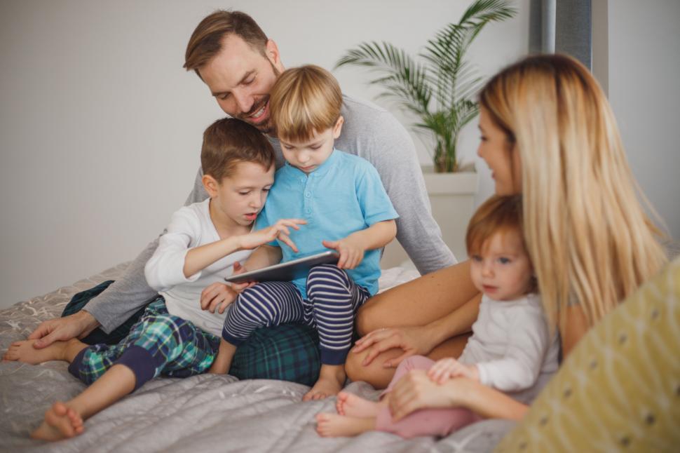 Free Image of Family with children using tablet on bed 