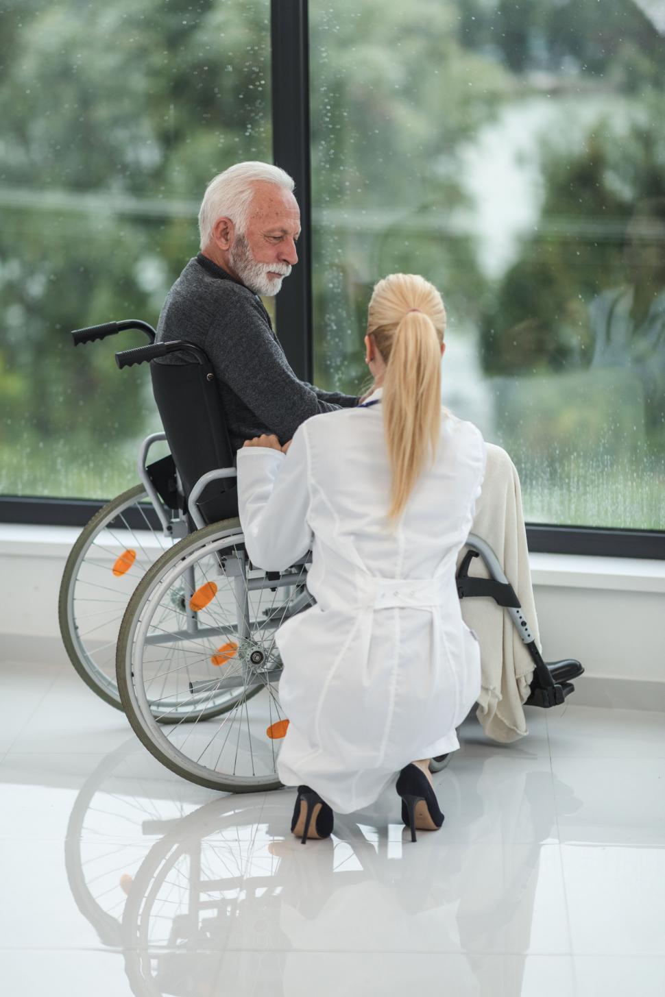Free Image of Elderly man in wheelchair speaking to nurse 