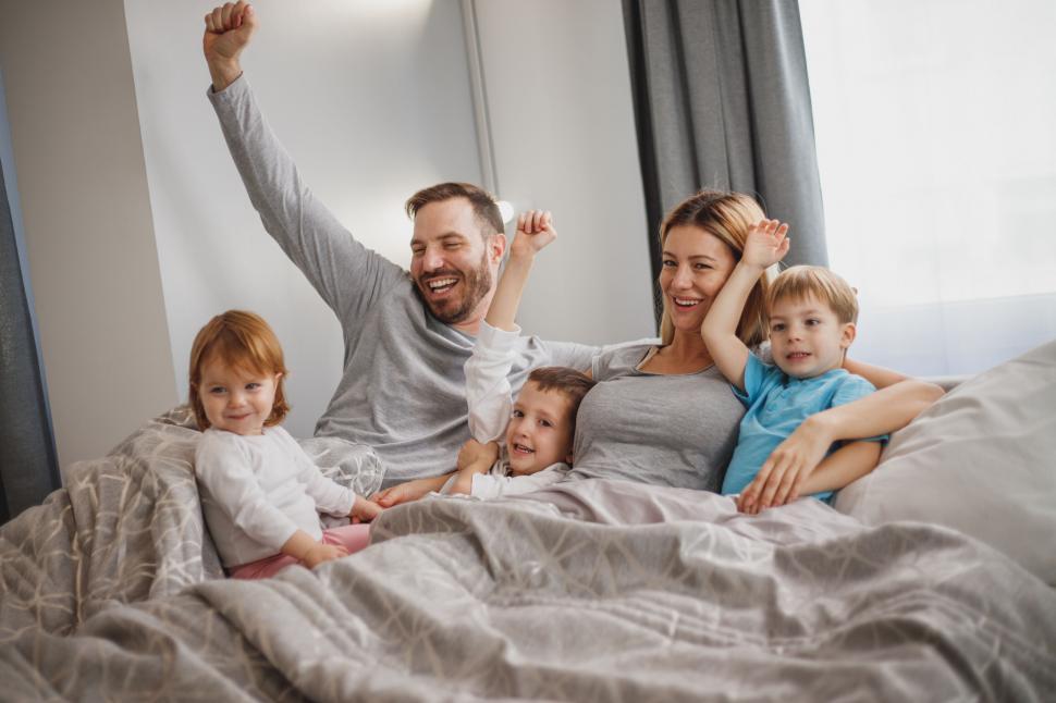 Free Image of Happy family in bed smiling and stretching 