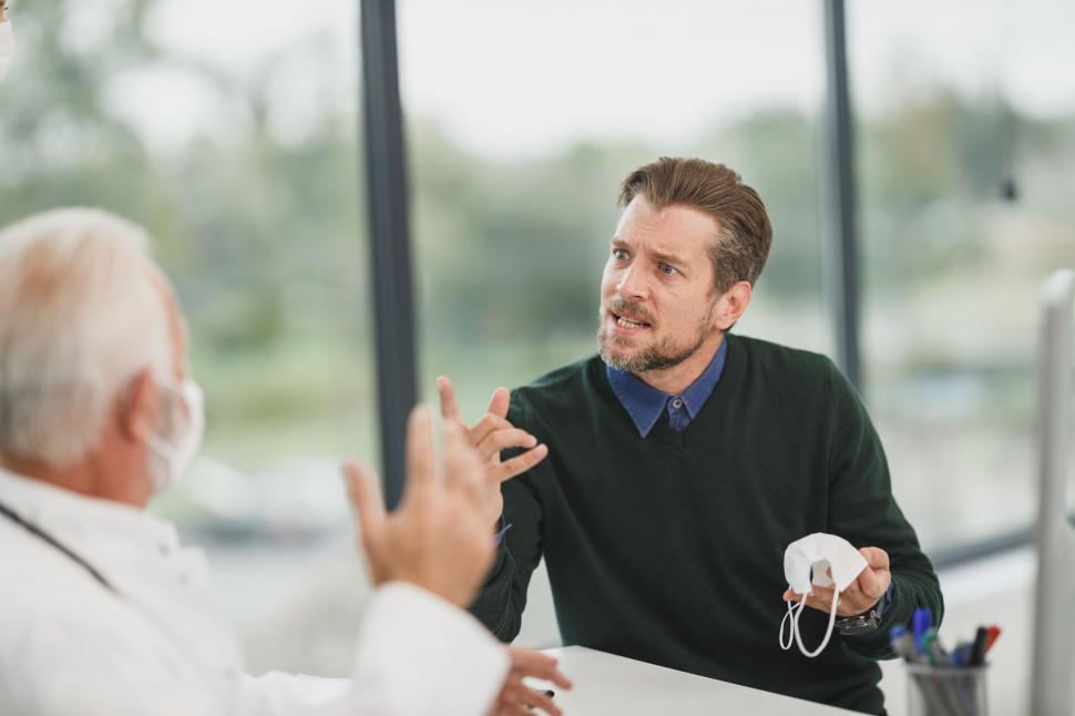Free Image of Patient discussing with doctor while holding a mask 