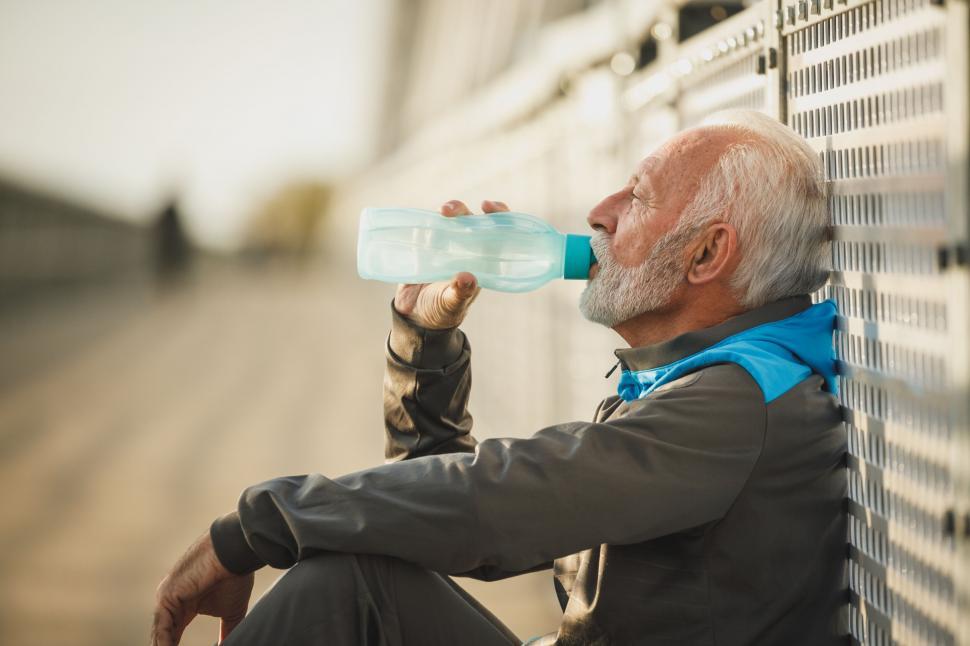 Free Image of Senior man resting with water bottle 