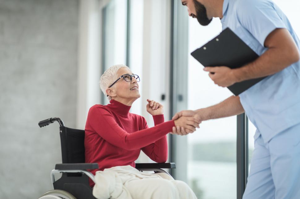 Free Image of Nurse greeting patient in wheelchair 