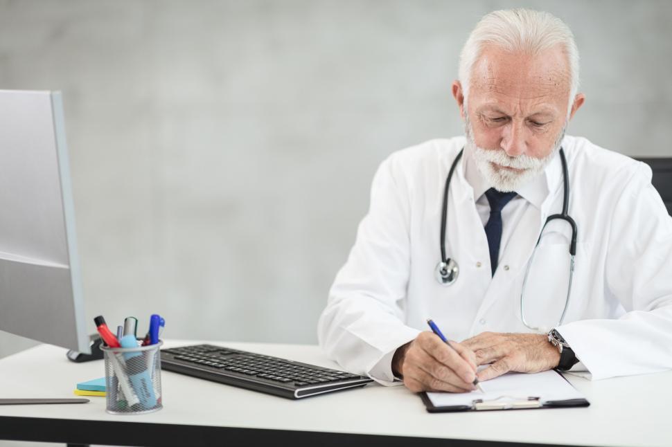 Free Image of Senior doctor writing in medical office 