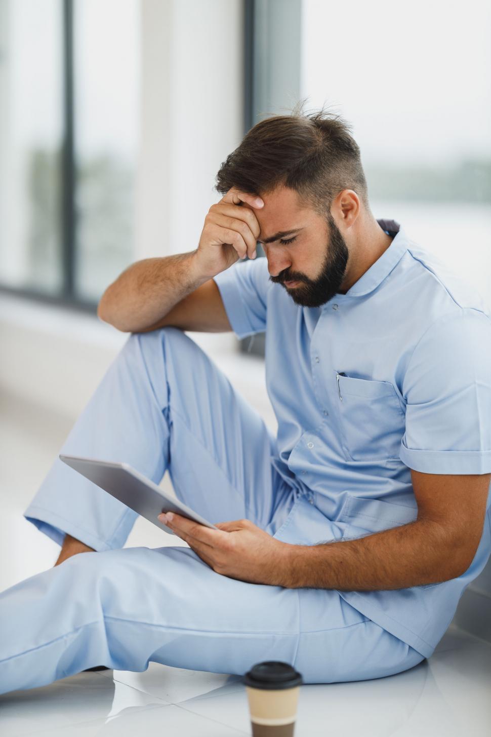 Free Image of Male nurse feeling stressed in hospital corridor 