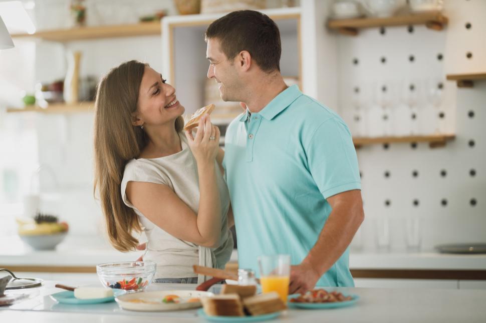 Free Image of Couple tasting food in a cozy kitchen 