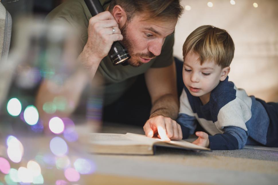 Free Image of Father and son reading book with flashlight 