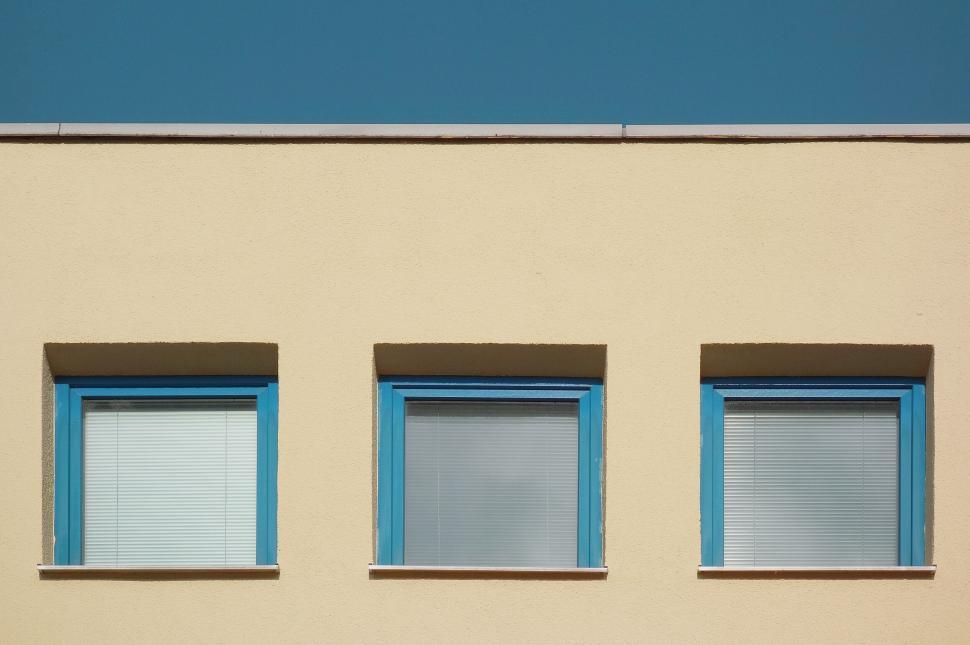 Free Image of Three blue window shutters on beige wall 