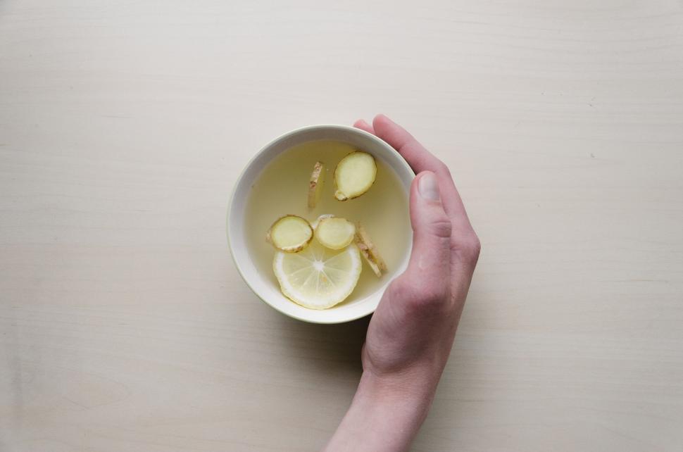 Free Image of Close-up of a hand holding a bowl with lemon and ginger 